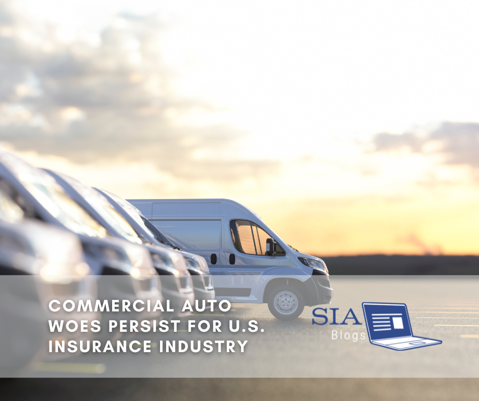 A row of commercial vehicles is lined up in the foreground, with a focus on one van in the center, set against a sunset or early morning sky. The scene represents the ongoing challenges faced by the U.S. insurance industry in the commercial auto sector.